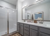 Thumbnail 17 of 56 - A bathroom with a white sink, a mirror, and a shower with a glass door.