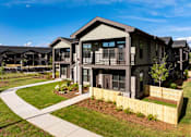 Thumbnail 44 of 50 - an apartment building with a yard and a sidewalk