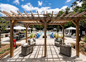 Thumbnail 38 of 50 - a patio with a pergola and chairs around a pool
