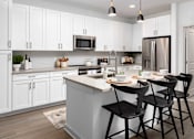 Thumbnail 10 of 50 - Two-Bedroom Apartments in Acworth, GA - The Brookstone - Open Kitchen with Premium Stainless Steel Appliances, Quartz Countertops, Designer Tile Backsplash, White Cabinetry, Island/Breakfast Bar with Seating, Pendant Lights, and Wood-Grain Plank Flooring.