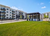 Thumbnail 21 of 26 - A grassy area in front of apartment buildings with a small pavilion.