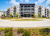 Thumbnail 3 of 26 - A large building with a black entrance and a sign that says "Inco" is surrounded by other buildings and landscaping.