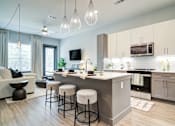 Thumbnail 5 of 26 - A modern kitchen with a bar area and a living room area.