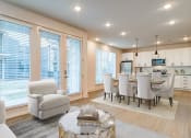 Thumbnail 6 of 28 - Luxury Apartments For Rent In Huntsville, AL - The Collins - Open-Concept Living Room With Wood-Style Flooring, Area Rug, Armchair, Coffeetable, High Ceilings, Custom Lighting, Abundant Windows With Blinds, and View of Dining Area and Kitchen