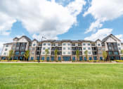 Thumbnail 53 of 56 - a large apartment building with a green lawn in front of it