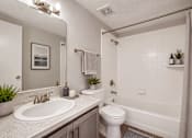 Thumbnail 6 of 22 - A bathroom with a white toilet, sink, and bathtub.