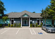 Thumbnail 17 of 22 - A parking lot in front of a building with a car parked in a handicap spot.