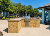 Thumbnail 13 of 22 - A stone barbecue grill is in the middle of a concrete patio.