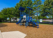 Thumbnail 14 of 22 - A playground with a blue slide and a brown surface.