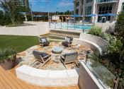 Thumbnail 32 of 44 - a patio with a fire pit and a pool in the background