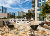 Thumbnail 33 of 44 - an outdoor patio with a firepit and lounge chairs with a city skyline in the background