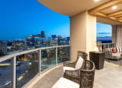 Thumbnail 42 of 44 - a balcony with two chairs and a table with a view of the city at night