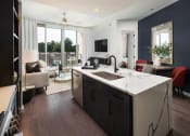 Thumbnail 18 of 44 - a kitchen with dark cabinets and a white counter top in front of a living room with a