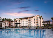 Thumbnail 1 of 31 - a swimming pool at dusk with an apartment building in the background