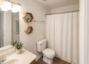Thumbnail 7 of 15 - A white bathroom with a toilet, sink, and shower curtain.