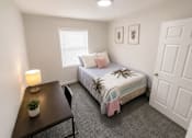 Thumbnail 9 of 15 - A bedroom with a bed, nightstand, and a plant.