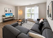Thumbnail 5 of 15 - A living room with a grey couch and a painting on the wall.