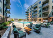 Thumbnail 2 of 28 - a pool with chairs and tables in front of an apartment building
