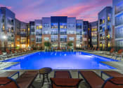 Thumbnail 37 of 45 - a swimming pool at night with an apartment building in the background