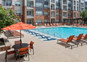 Thumbnail 35 of 45 - a swimming pool with chairs and an umbrella in front of an apartment building