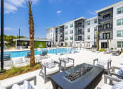 Thumbnail 14 of 29 - Dog-Friendly Apartments in Panama City Beach, FL - The Tyde - Resort-Style Pool with Tanning Shelf, Submerged and Poolside Lounge Chairs, and Fire Pits with Comfortable Seating.