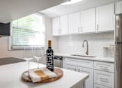 Thumbnail 2 of 25 - A kitchen with a wine bottle and glasses on the counter.