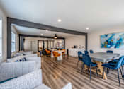 Thumbnail 15 of 25 - A modern living room with a grey sofa, a dining table with blue chairs, and a painting on the wall.