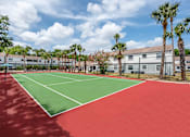 Thumbnail 22 of 25 - A tennis court with red and green surface and white lines.
