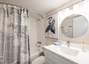 Thumbnail 9 of 25 - A bathroom with a white sink and a grey and white shower curtain.