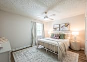 Thumbnail 11 of 25 - A bedroom with a bed, nightstand, and a ceiling fan.