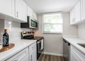 Thumbnail 3 of 25 - A kitchen with white cabinets and a black microwave.
