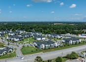 Thumbnail 45 of 49 - A large apartment complex is surrounded by trees and a road.