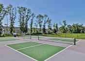Thumbnail 35 of 49 - A tennis court surrounded by trees and a fence.