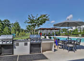 Thumbnail 32 of 49 - A patio with a grill, table, and chairs.