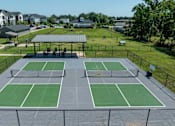 Thumbnail 34 of 49 - A tennis court with a green surface and a black fence surrounding it.