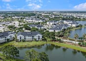 Thumbnail 42 of 45 - A large white building with a black roof is surrounded by a lake.