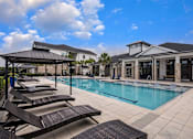 Thumbnail 14 of 45 - A pool area with sun loungers and a pavilion.