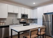 Thumbnail 20 of 45 - A kitchen with a table and chairs in front of a refrigerator.