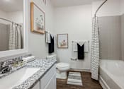Thumbnail 25 of 45 - A bathroom with a white tub, toilet, and sink.