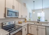 Thumbnail 3 of 18 - Dog-Friendly Apartments In Hermitage, TN - Kitchen With Stainless Steel Appliances, Granite Countertops, Hardwood Inspired Flooring, European-Style Cabinetry, And Built-In Microwave.