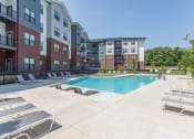 Thumbnail 16 of 18 - Hermitage Apartments - Expansive Pool And Pool Deck, Lounge Chairs, And Maintained Landscaping. Apartments Are In The Background.