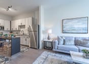 Thumbnail 4 of 18 - a living room with a couch and a chair in front of a kitchen with stainless steel appliances