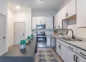 Thumbnail 1 of 18 - a kitchen with white cabinets and gray countertops