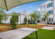 Thumbnail 31 of 37 - a ping pong table sits in the middle of a grassy area in front of a