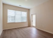 Thumbnail 8 of 19 - the living room of an empty home with wood flooring and a large window