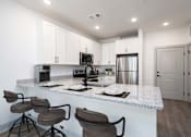 Thumbnail 7 of 33 - A kitchen with a white countertop and brown barstools.