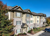 Thumbnail 1 of 30 - an apartment building with brick and stone exterior and trees