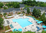 Thumbnail 1 of 59 - A large swimming pool surrounded by a grassy area and trees.