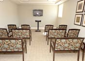 Thumbnail 10 of 23 - A room with a television and chairs with floral patterns.