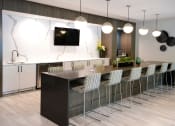 Thumbnail 15 of 31 - a kitchen with a long island with chairs and a tv